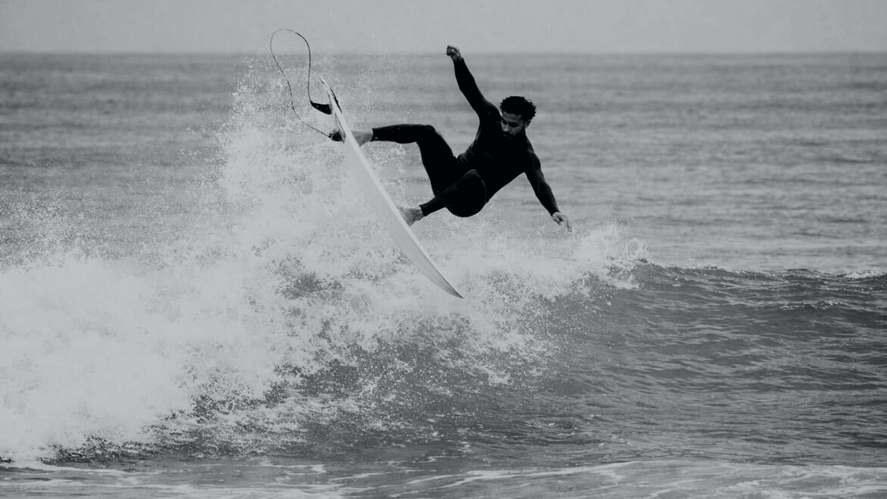 Surfer above the lip of a wave in black and white